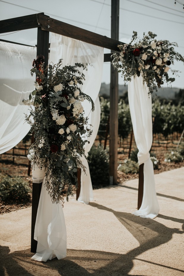 wedding arch draped in fabric and florals