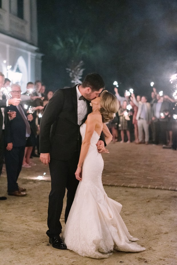 Bride and groom kiss surrounded by sparklers