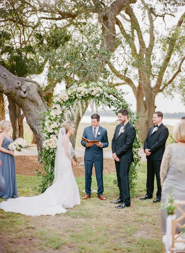Outdoor wedding ceremony with floral arch and officiant