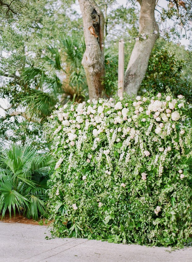 Outdoor wedding backdrop with lush green foliage and white flowers