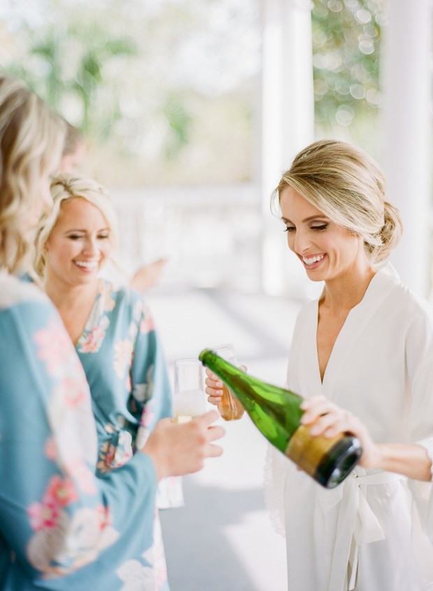 Bride pouring champagne for bridesmaids on wedding day