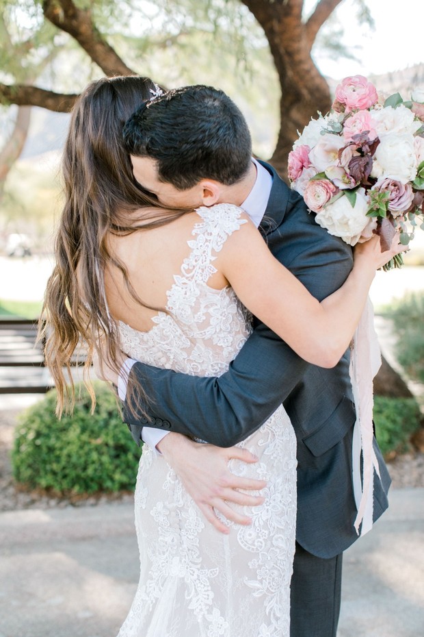 Newlyweds embracing bride in lace dress and bouquet