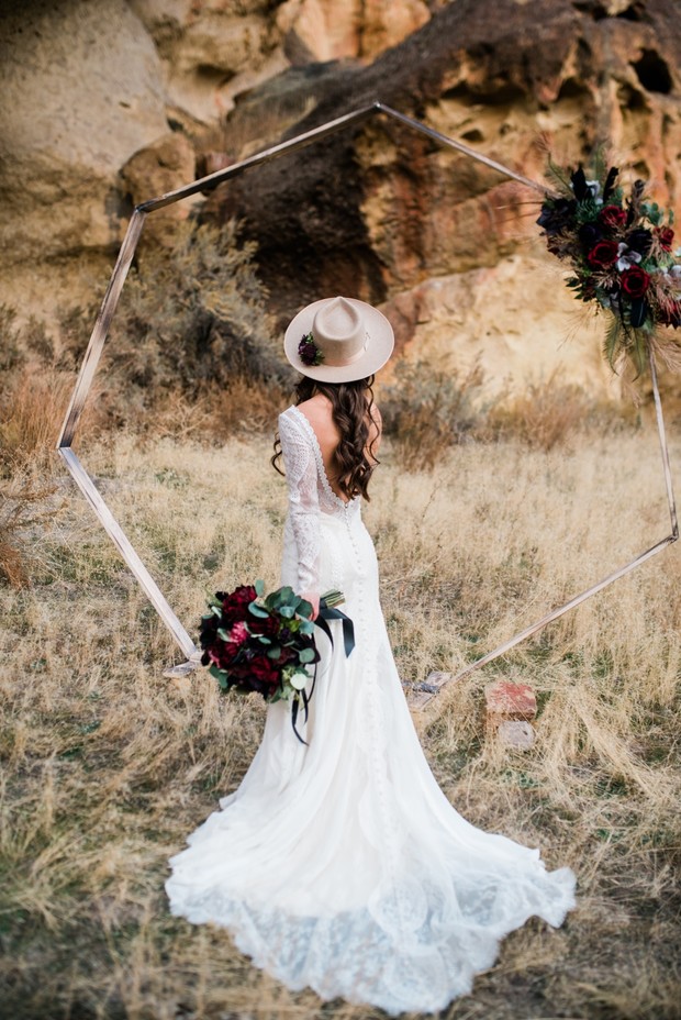 Bride with hat and bouquet at outdoor wedding altar