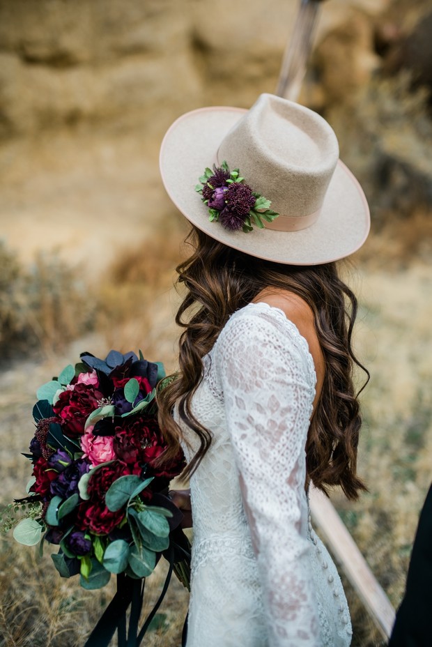 Bride in hat with flowers and dark romantic bouquet