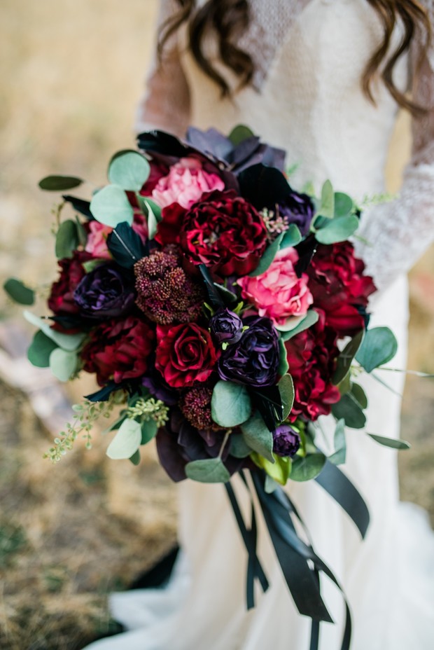 Bride holds dark red and pink wedding flower bouquet