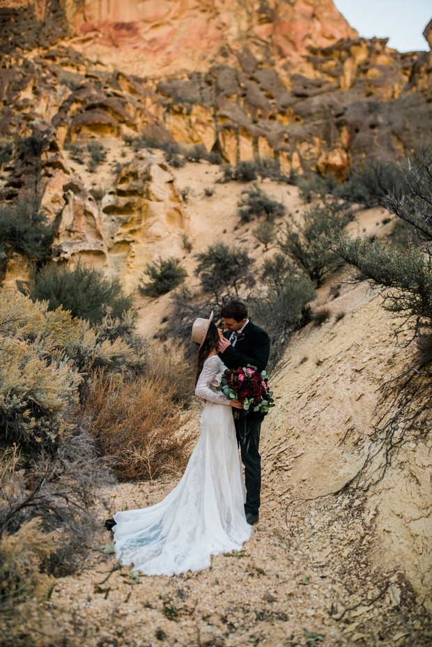 Bride and groom embrace in desert landscape wedding