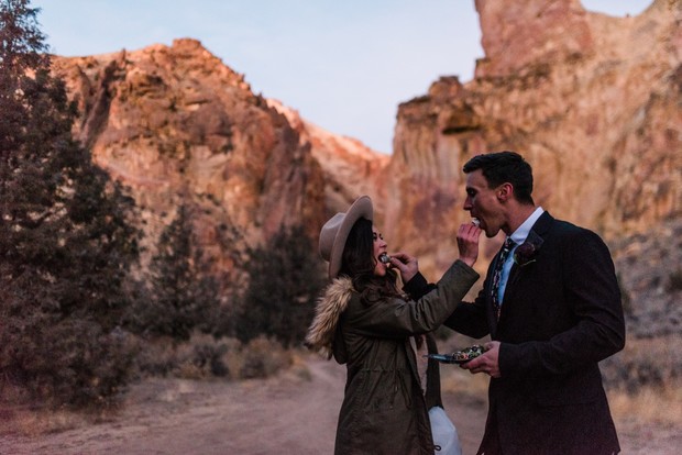 Couple feeding each other in a desert landscape during a wedding