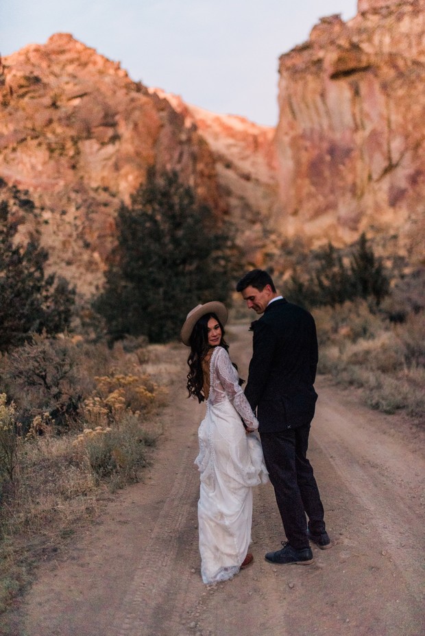 Bride and groom walking hand in hand on a dirt road after wedding