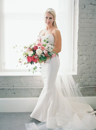 Elegant bride in a white gown holds a beautiful flower bouquet