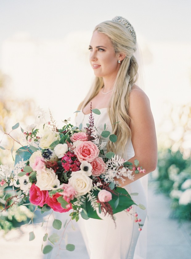 Bride holding colorful roses bouquet in wedding dress