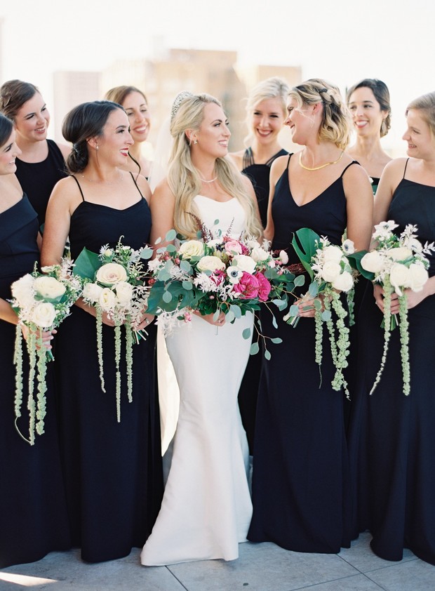 Bride with bridesmaids in black dresses holding bouquets
