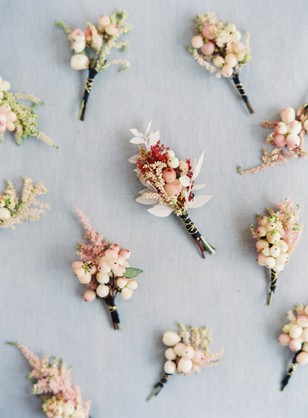 Boutonnieres with berries and flowers on a blue surface