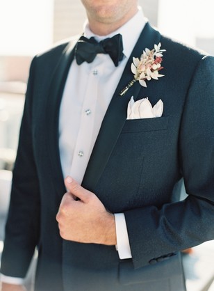 Groom in black tuxedo with bow tie and boutonniere