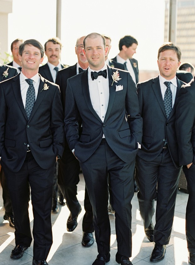 Groomsmen in stylish black suits pose for a wedding photo