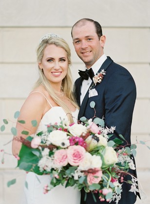 Happy couple smiling on their wedding day, holding flowers