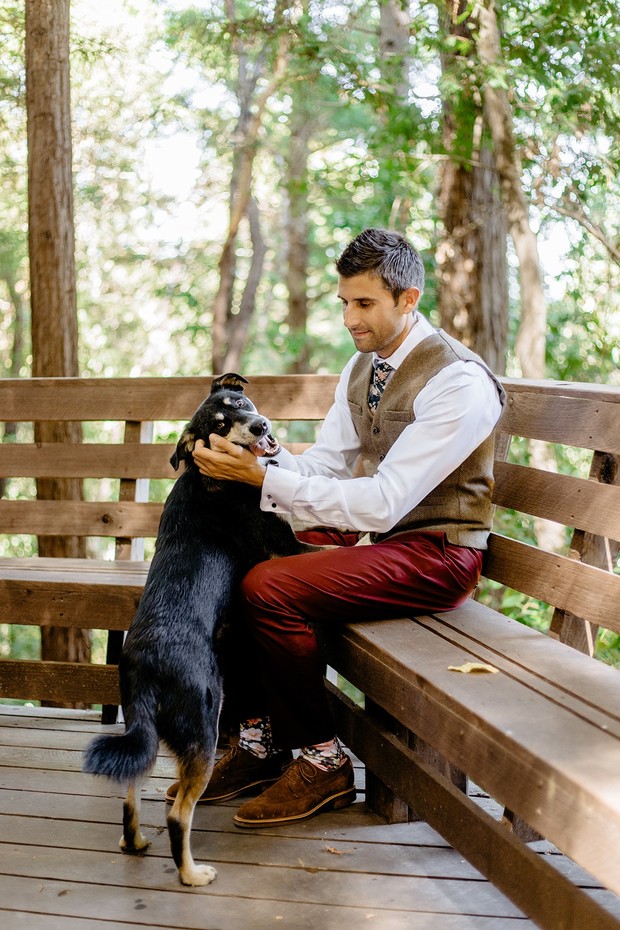 Man pets a dog on a wooden bench in a forest setting