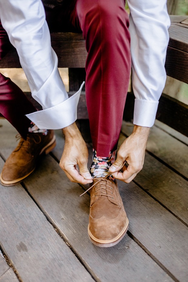 Man tying brown shoelaces while wearing colorful socks and stylish outfit