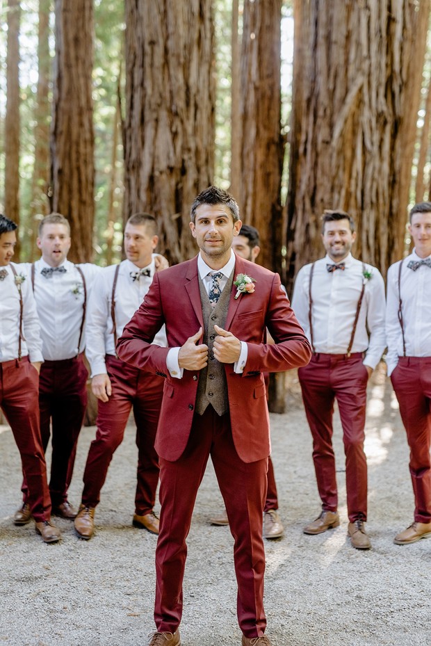 Groom and groomsmen in burgundy suits posing for a wedding photo