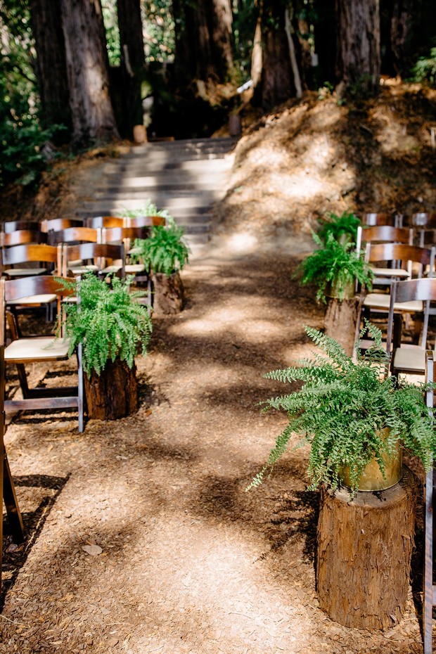 Outdoor wedding aisle decorated with ferns in a forest setting
