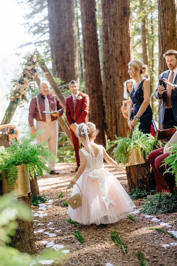Flower girl walks down the aisle at a beautiful outdoor wedding