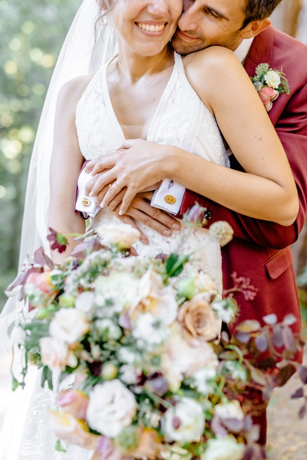 Happy couple embrace on their wedding day with beautiful bouquet