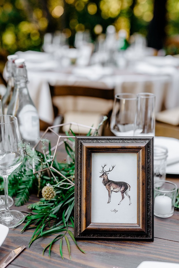Wedding table setting with deer art frame and greenery