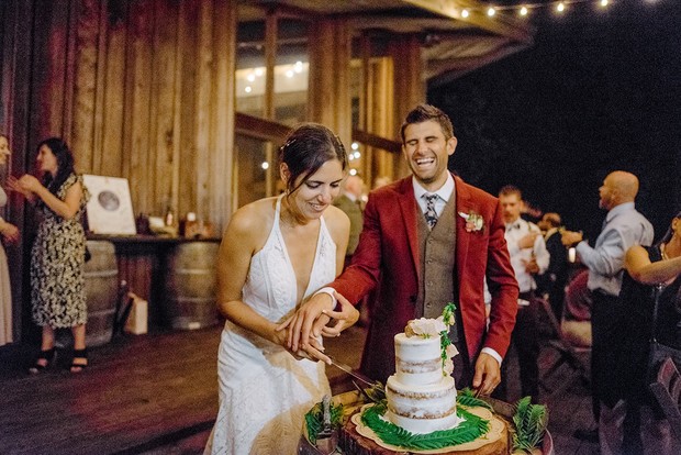Bride and groom happily cutting the cake at their rustic wedding