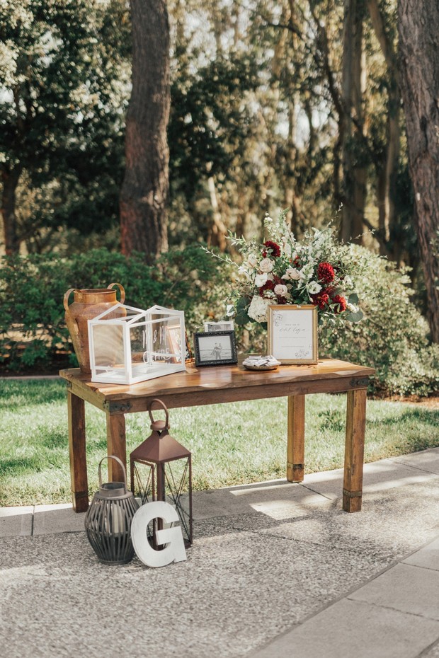 Wedding decor with flowers lanterns and G on a wooden table