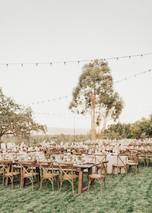 Outdoor wedding reception setup with elegant wooden tables and chairs