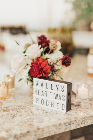 Sign saying Ally's Heart Was Robbed beside flowers, wedding decor