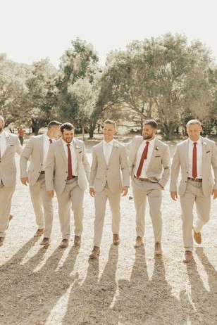 Groomsmen in matching suits walking towards the camera outdoors