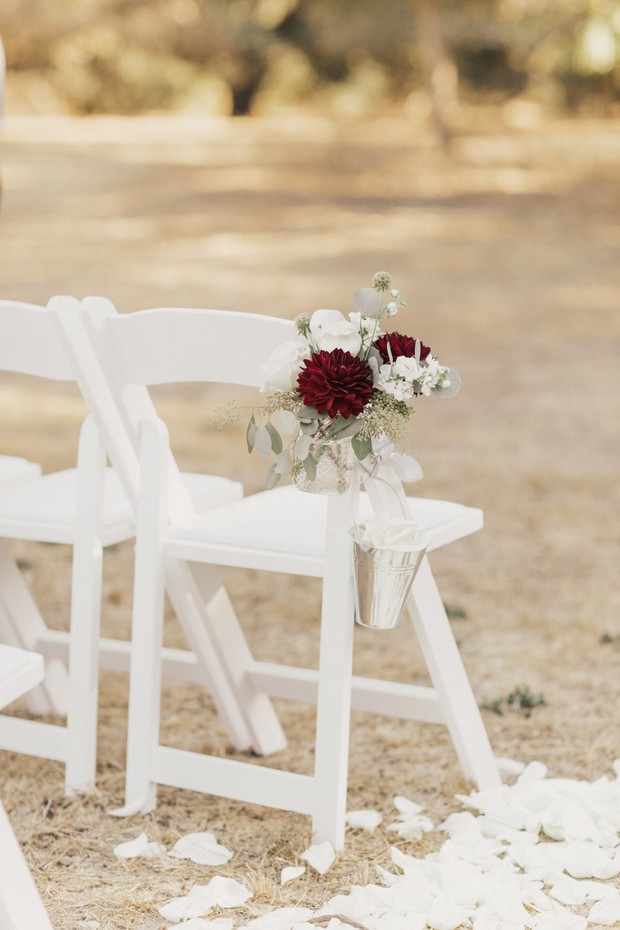 White wedding chairs with floral decoration, outdoor ceremony decor