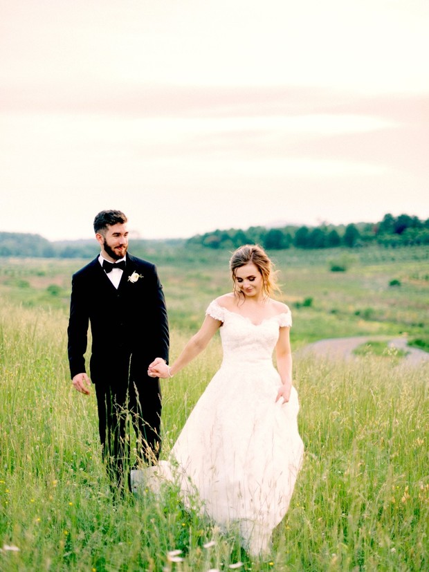 Bride and groom walk in a field on their wedding day