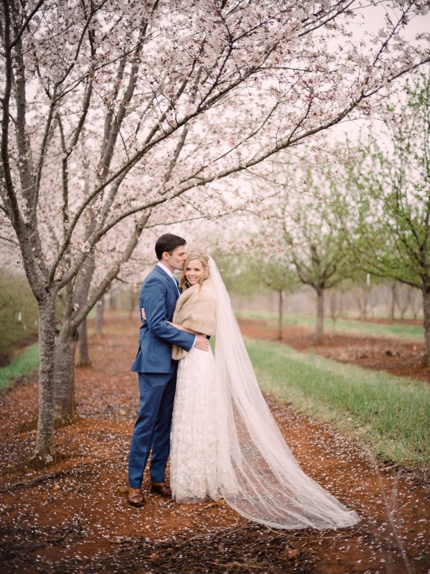 Bride and groom embrace under blooming cherry trees