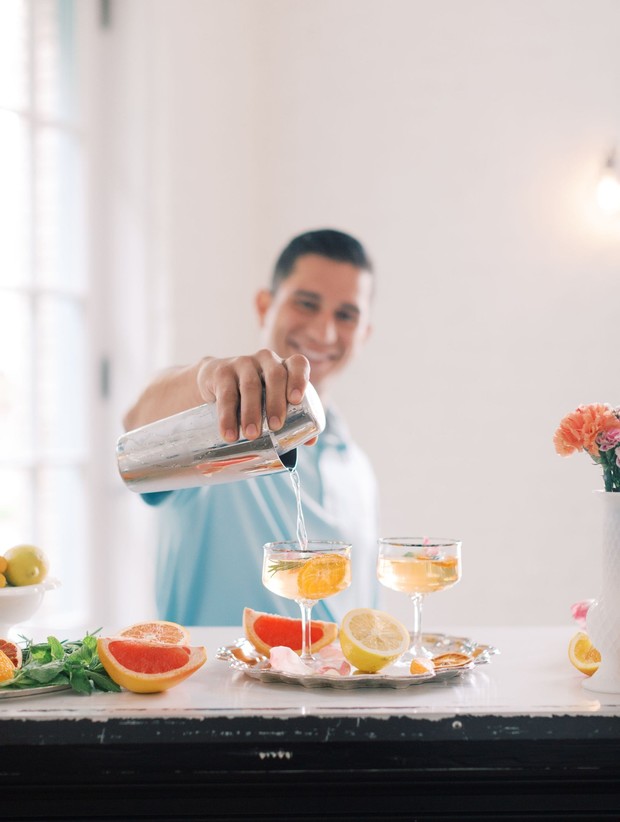Man pours citrus cocktail from shaker into glasses
