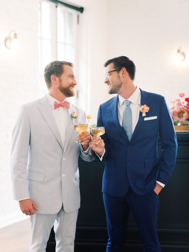 Two grooms toast champagne at their stylish wedding