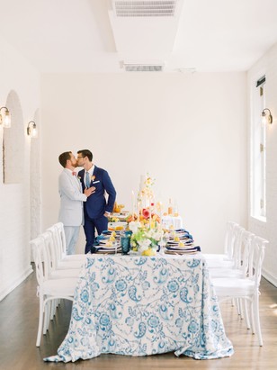 Two grooms share a kiss at a beautifully decorated wedding reception
