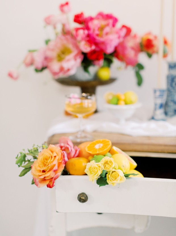 Floral arrangement with citrus fruits on a white dresser