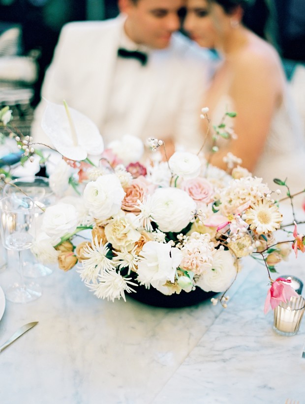 Elegant floral centerpiece at a wedding reception with blurred couple
