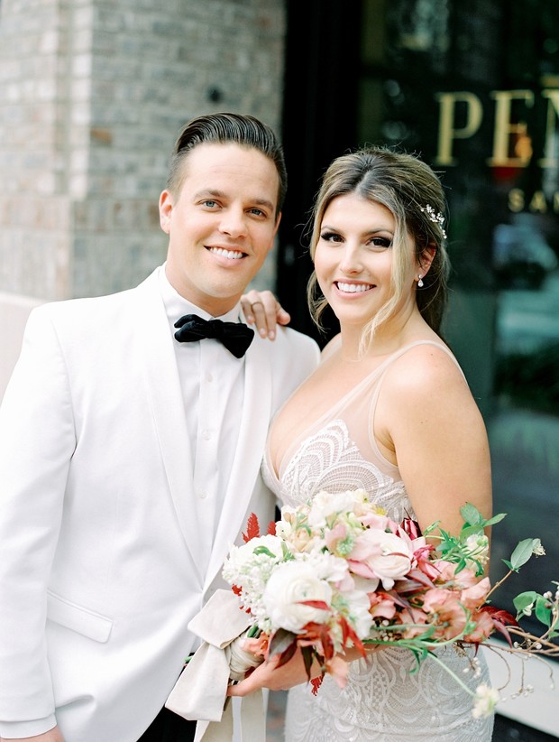 Happy couple smiling on their wedding day, with beautiful floral bouquet