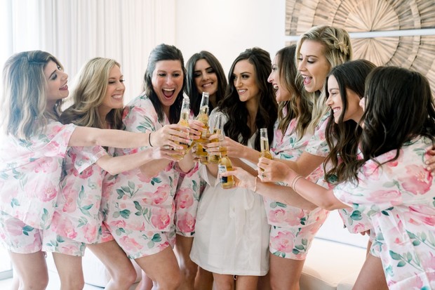 Bridesmaids toasting with beers in matching floral pajamas, wedding day