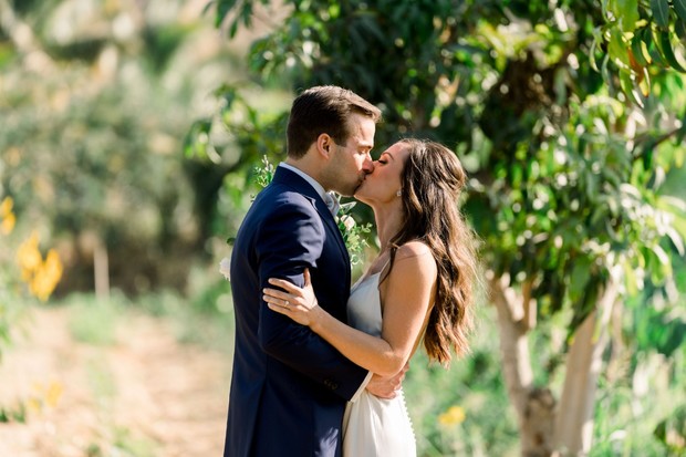 Newlyweds share a romantic kiss under the sunlight on their wedding day