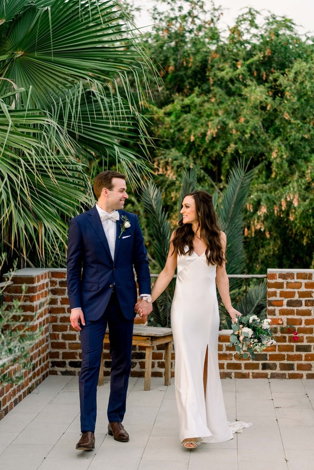 Happy bride and groom holding hands at outdoor wedding