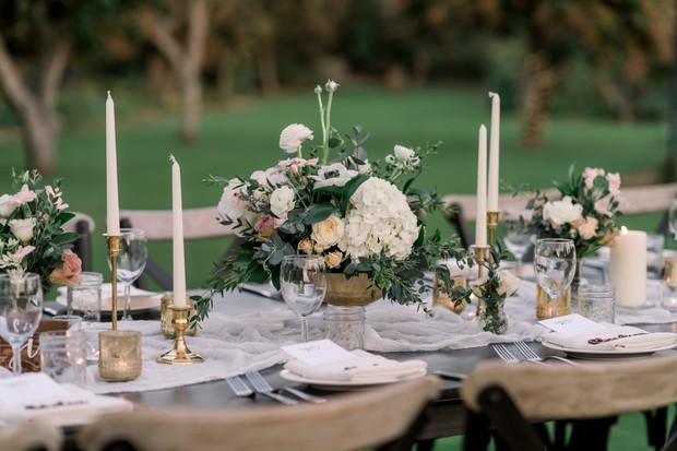 Elegant wedding table setting with flowers and candles on a green backdrop