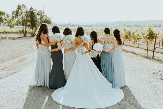 Bride and bridesmaids embrace outdoors wedding day