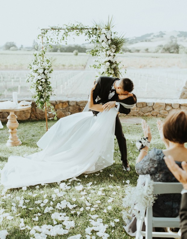 Newlyweds share a passionate kiss after saying I do at outdoor wedding