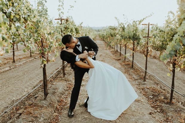 Romantic wedding couple kissing in a vineyard setting