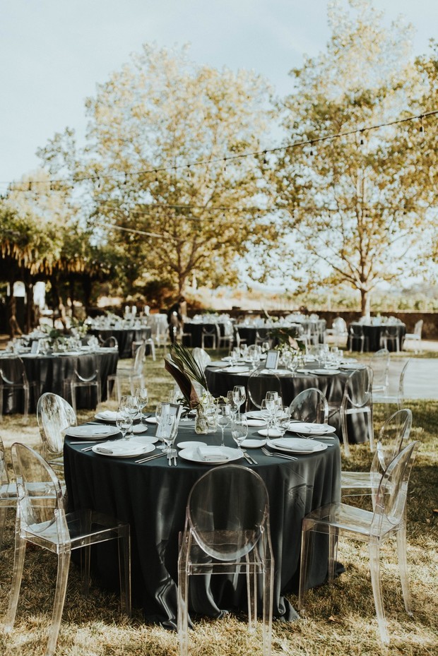 Outdoor wedding reception tables with clear chairs and black linens