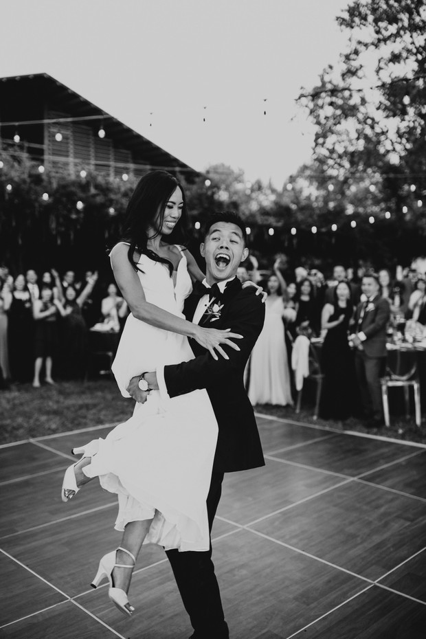 Groom lifts happy bride on dance floor at wedding reception