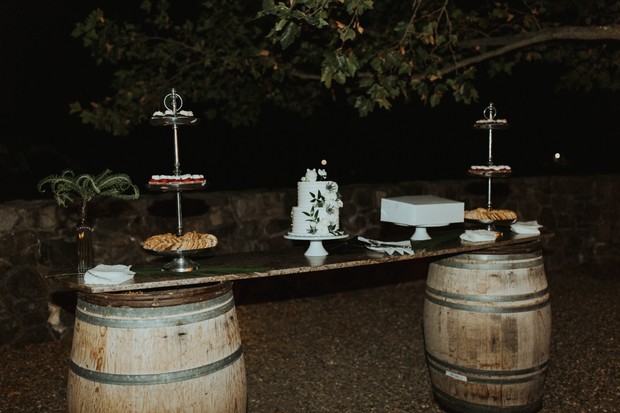 Wedding cake and desserts on a rustic bar with barrel base